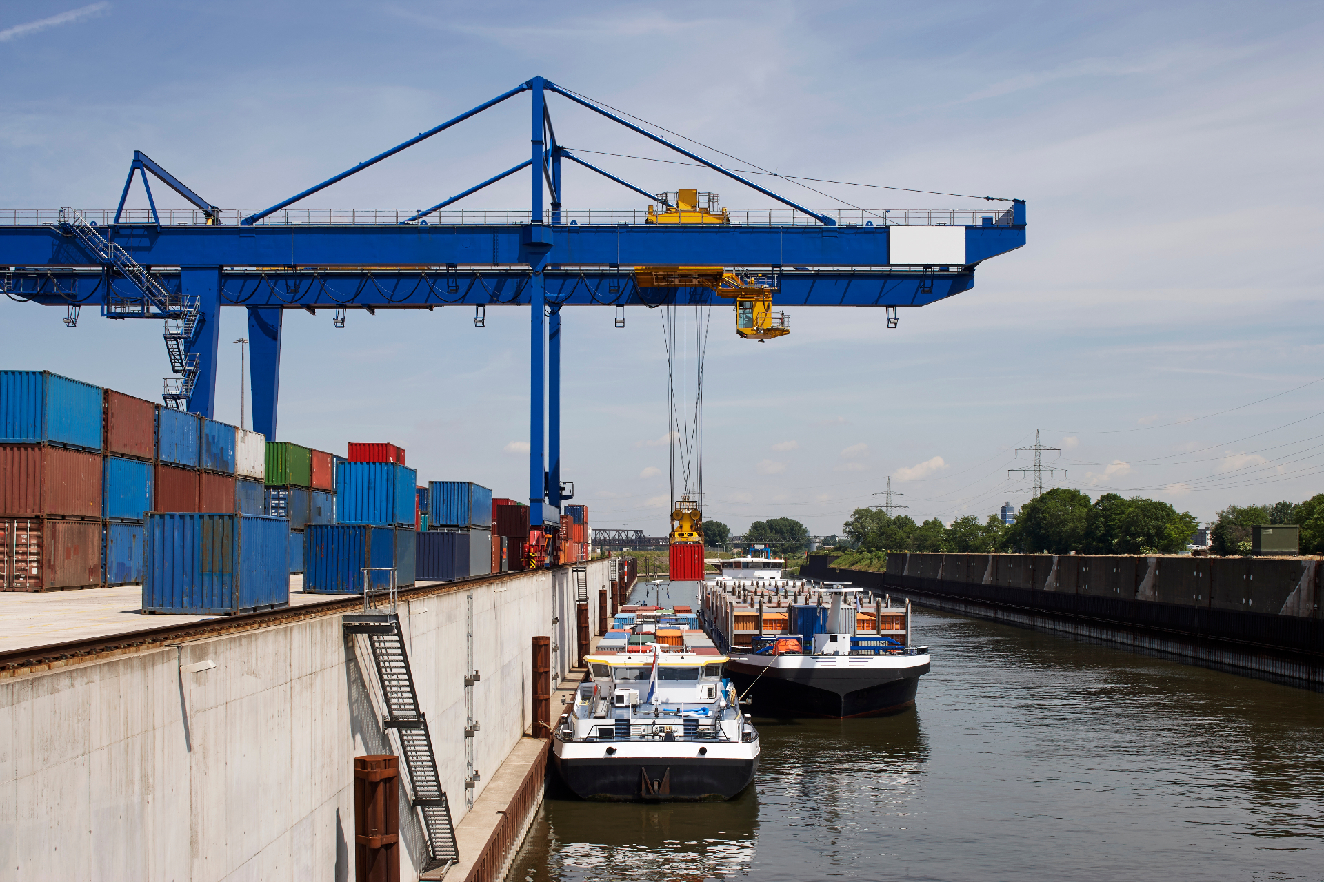 Container port crane loading barges at an industrial inland terminal — APAC supply chain coordination for petroleum and specialty oil shipments.